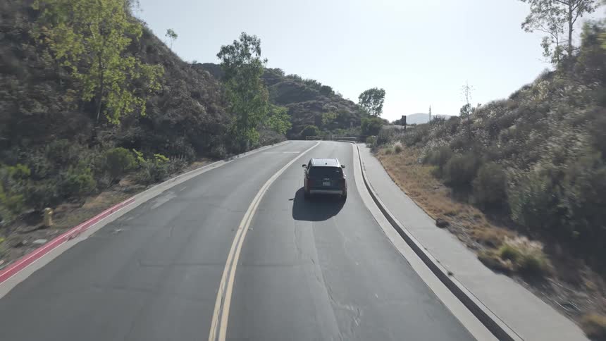 Car traveling on a road surrounded by mountains and vegetation