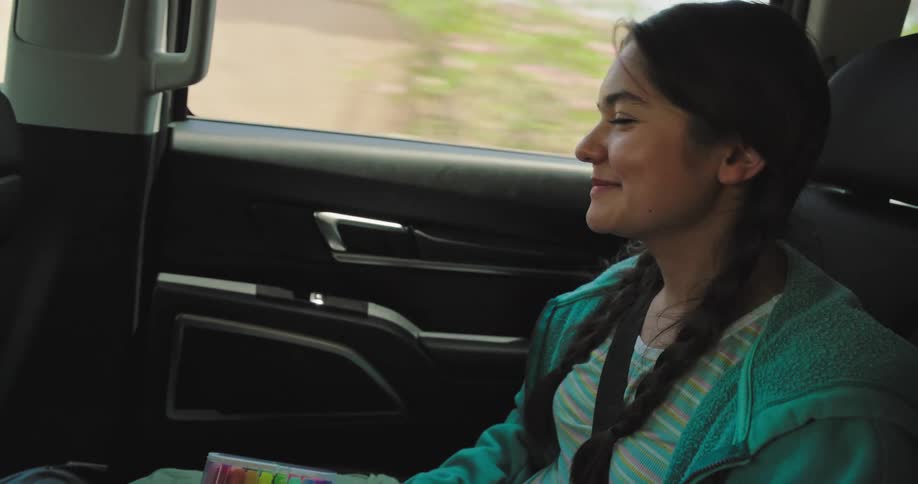 The girl smiles and laughs in the backseat of the car