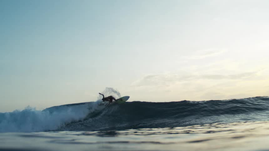 Surfer performs a maneuver on a wave at dusk