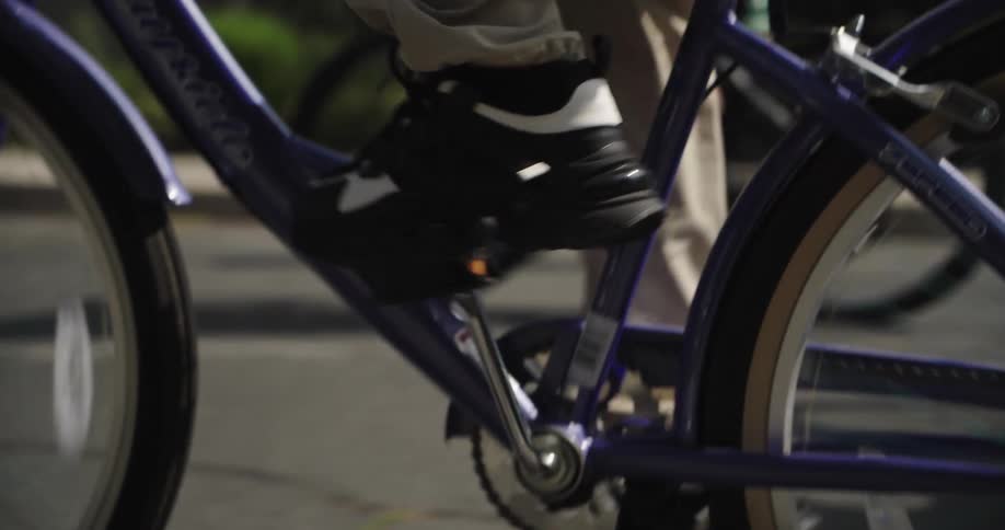 Legs of a small group of people riding bicycles through an urban neighborhood