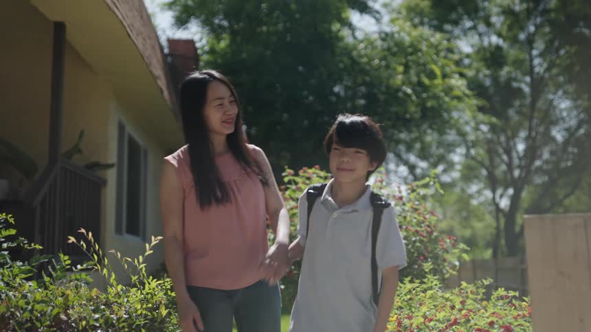 A mother watches her son go to school