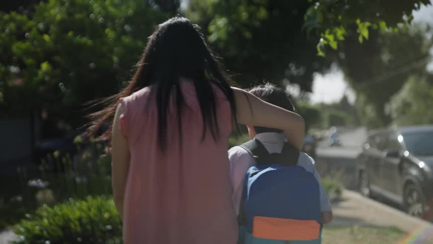 Mother walks with her son having her arm around his shoulder