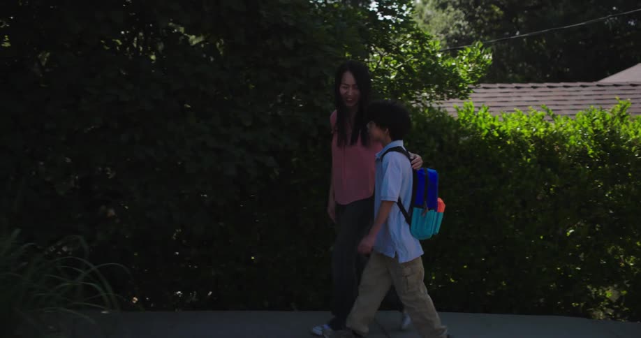 Mother and son walking together on a suburban sidewalk