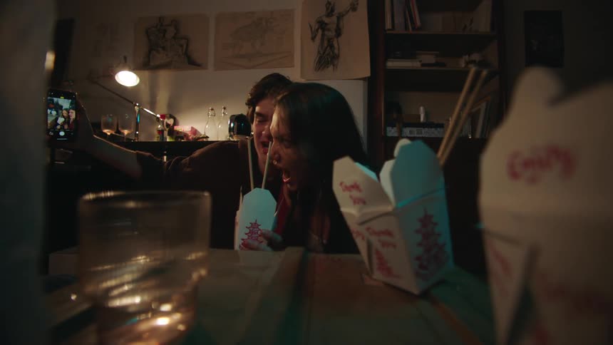 Couple sitting eating and drinking taking a selfie