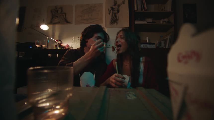 Couple sitting together eating with chopsticks and joking with each other