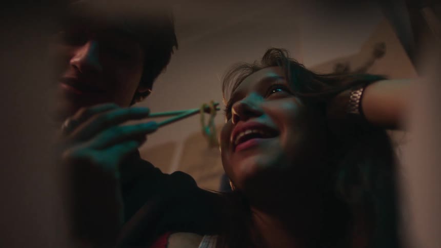 A couple eats noodles with chopsticks viewed from inside the takeout container