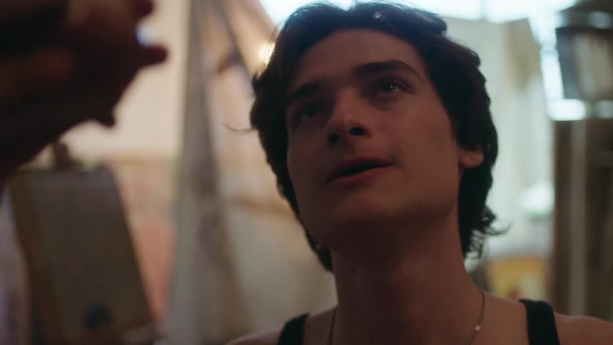 A man takes a drink while looking at someone