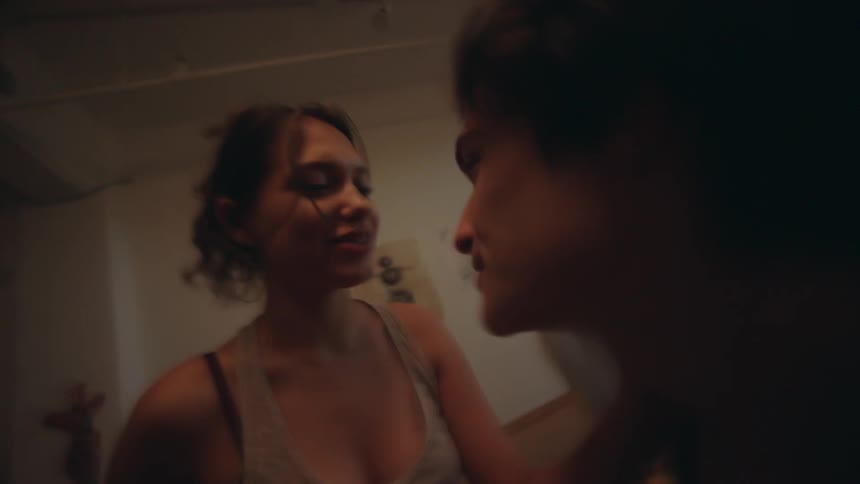 The video shows a blurry and shaky shot of two women facing each other in what appears to be an indoor setting with some furniture they are close and at times their faces are almost touching suggesting an intense or intimate interaction