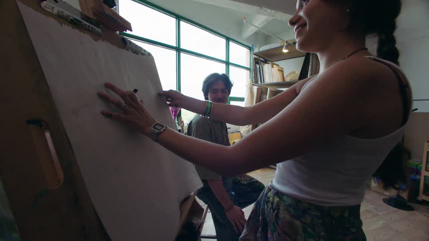 Woman placing a white sheet on a panel with a man next to her