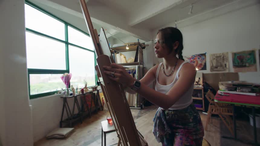 A woman covers the canvas with charcoal