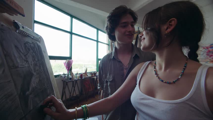 Man approaching a woman who is drawing