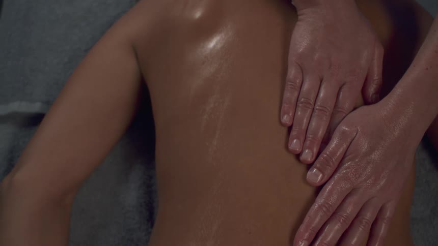 Pair of a persons hands massaging a womans back