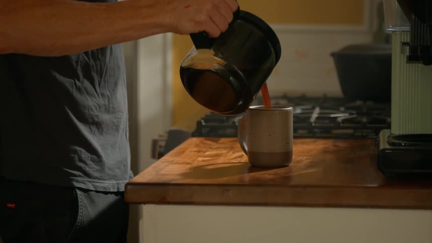 Person pouring coffee into a mug