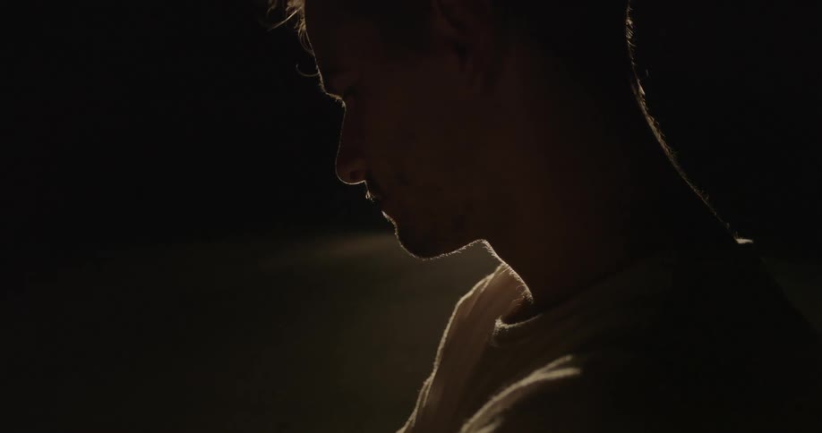 A person standing in front of a car in the dark