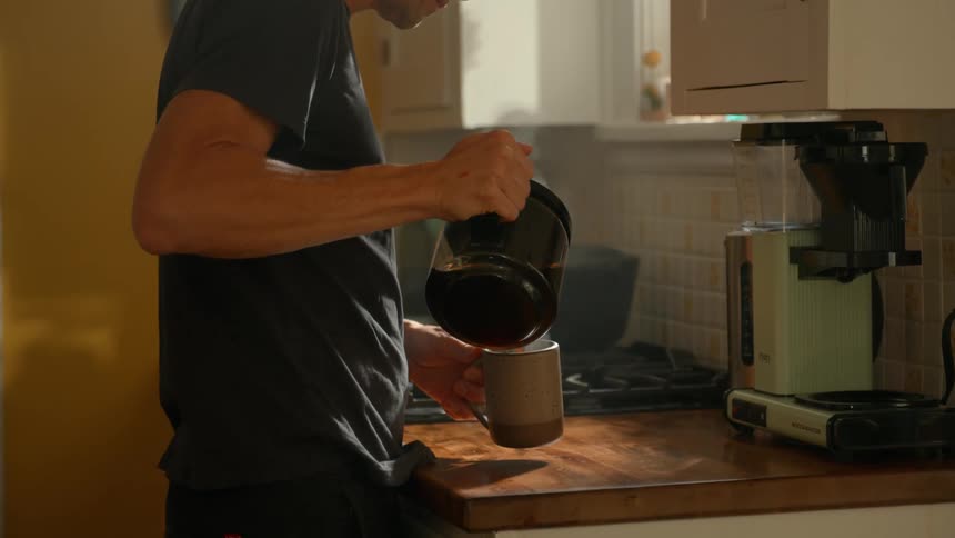 Man in the kitchen serving himself coffee