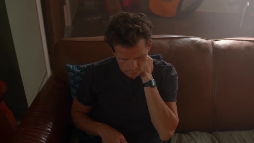 Man sitting on a leather sofa interacting with a laptop