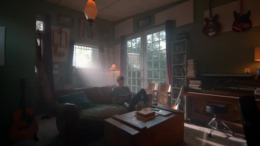 Man sitting down picking up and reading a book