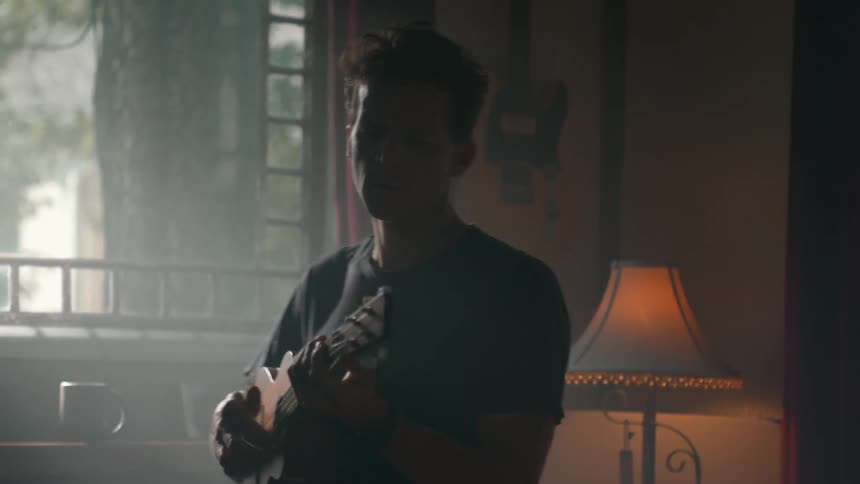 A man is pacing while playing the guitar