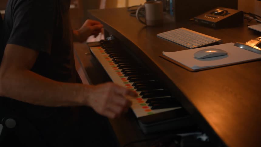Man sitting playing piano in front of a computer screen