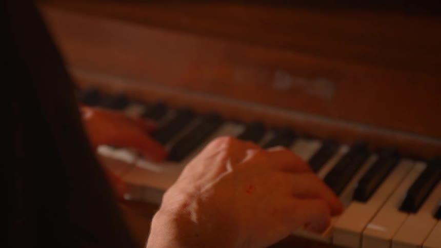 Hands playing a piano under warm lighting