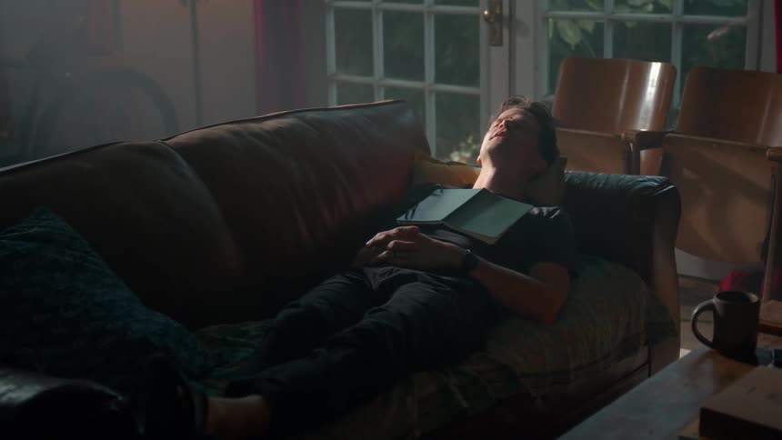Man lying on a sofa stretching his arms