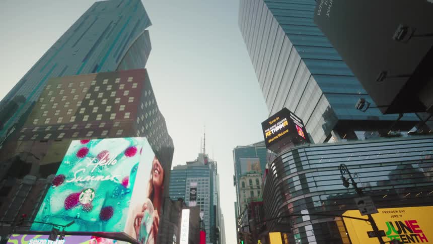 Skyscrapers tower over a busy city street with bright digital billboards in the morning