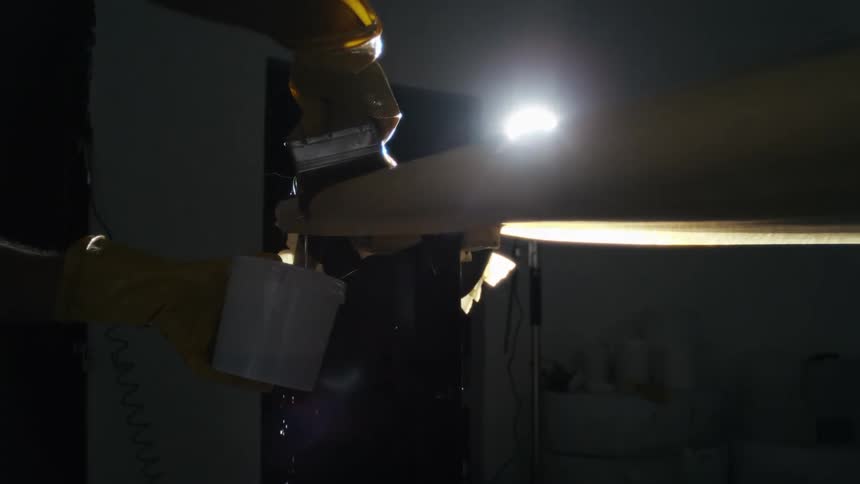 Pair of gloved hands applying liquid with a sponge to a surface