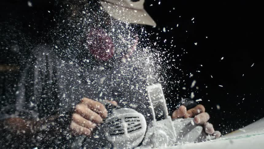 Person sanding material as dust flies in all directions