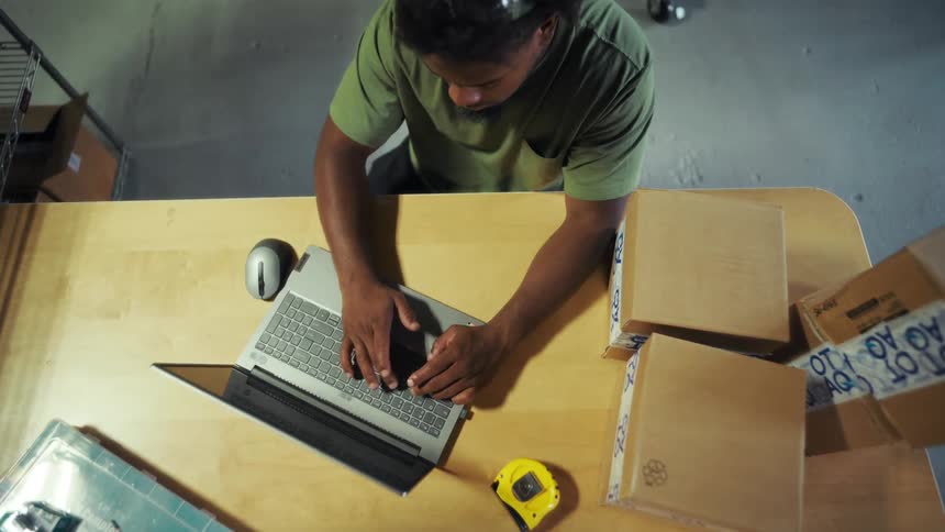 Man at a table sitting interacting with a laptop