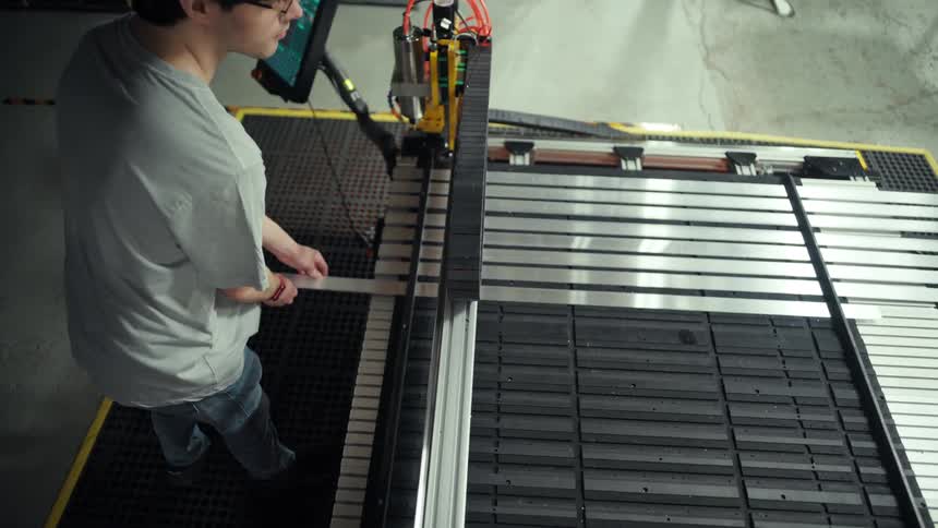 Man at an industrial machine placing a metal bar into the machine