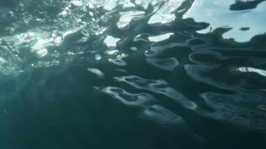 Gentle light rays and tiny particles from waves drift through ocean water