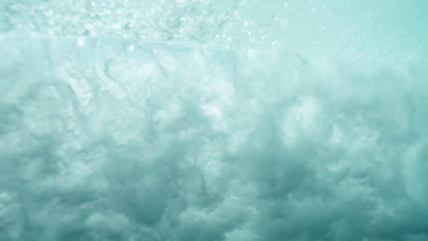 Aquamarine colored water with slow waves and bubble under light