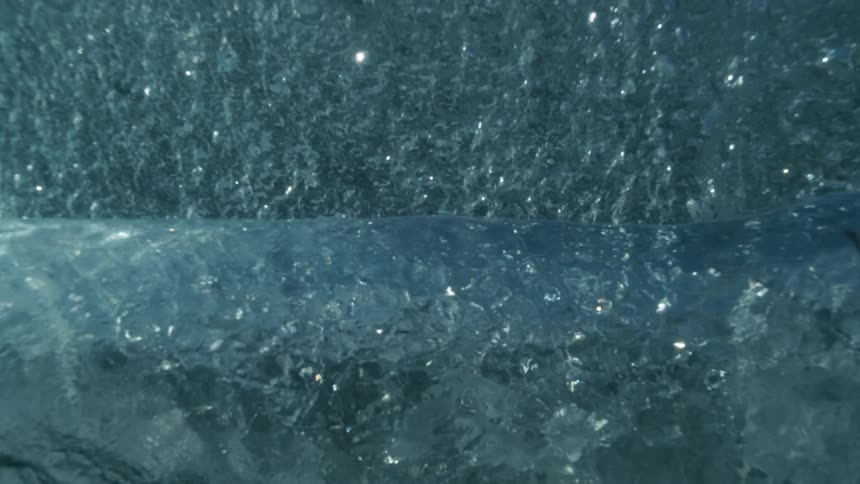 Underwater rolling waves and bubbles reflecting sunlight