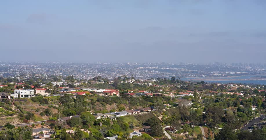 A sprawling hillside community overlooks the coastline with a beach curving along the edge of the city