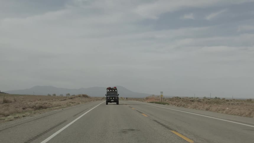 A jeep drives down a desert road