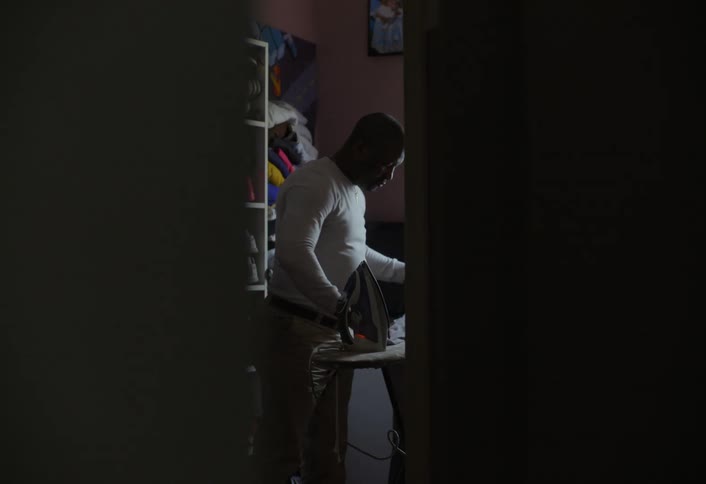 Man in a room of the house ironing clothes