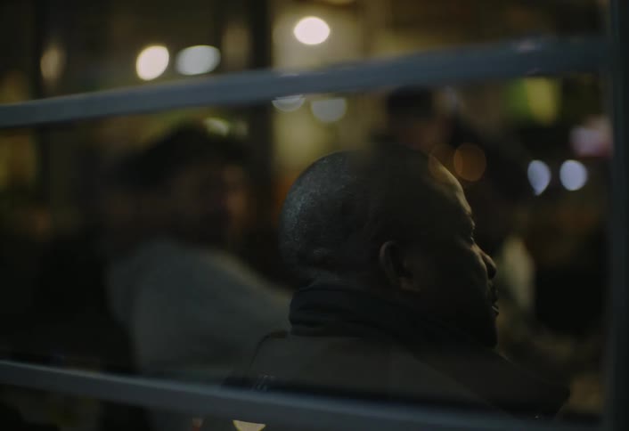 Man sitting inside a business with other people at night