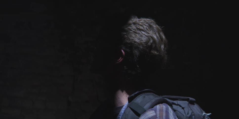 Man with a backpack inside a tunnel watching