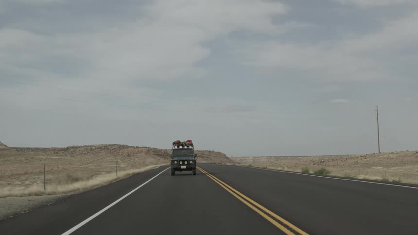 A jeep drives down a desert road