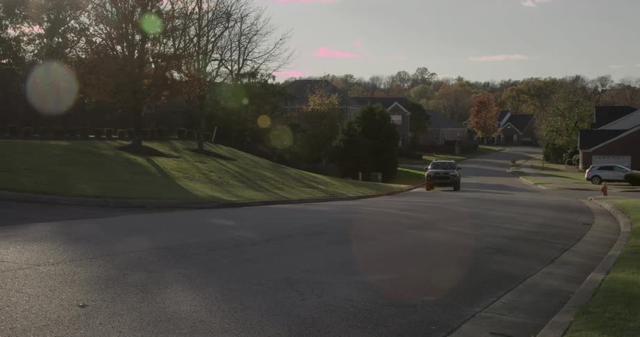 Suv car moving along a paved street in a leafy urban neighborhood