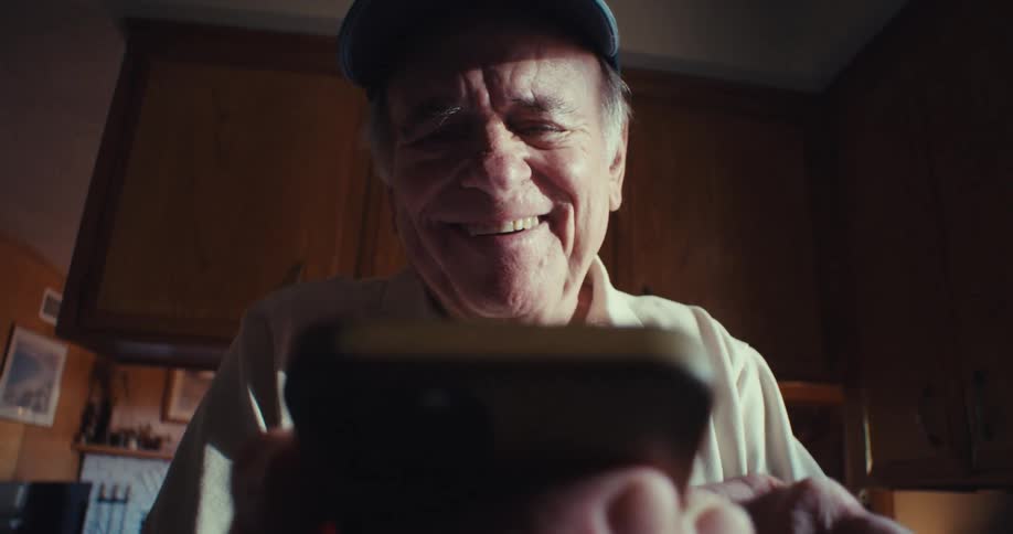 Happy elderly man interacting with smartphone