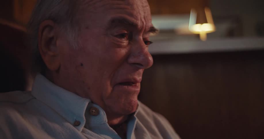The video features a closeup shot of an elderly man holding a smartphone he appears to be talking on the phone gesturing with his free hand