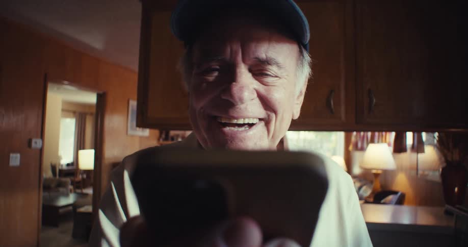 Happy elderly man waves while on a video call