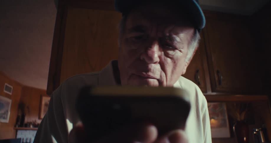 Elderly man with a happy expression interacting with a smartphone