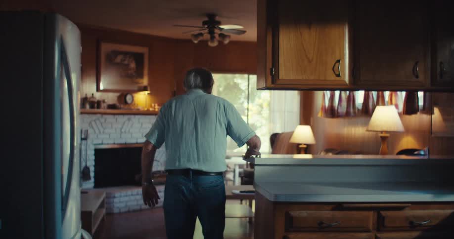 Elderly man walking slowly around the room in the house