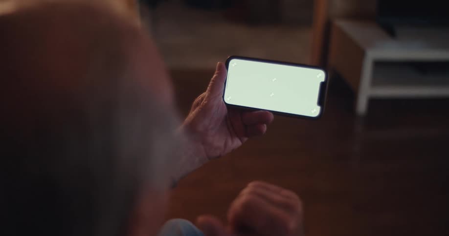 Elderly man watching his smartphone cheers and bounces in his seat