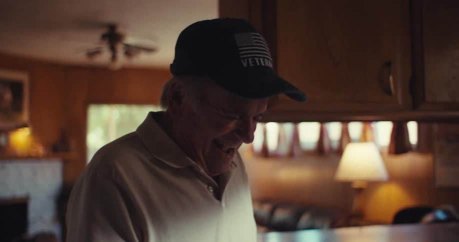 Elderly man wearing a cap with a happy expression walking through the rooms of the house