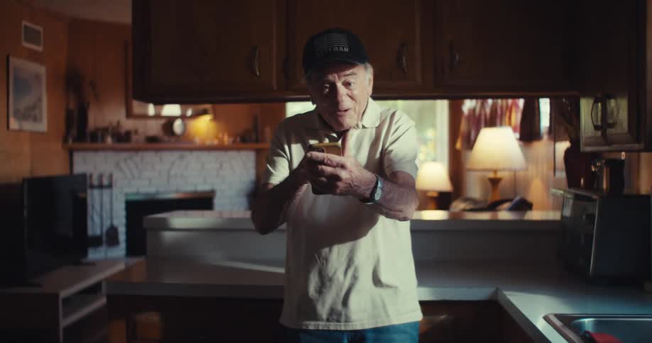 Happy elderly man waving goodbye while using a smartphone