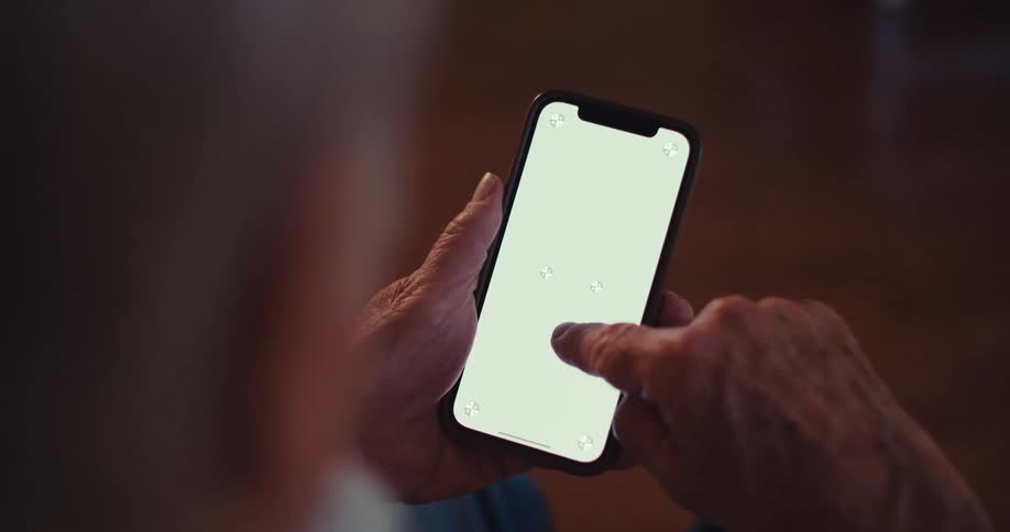 A man is sitting indoors scrolling through his phone