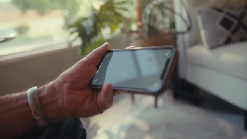 Elderly man closely watches smartphone sideways